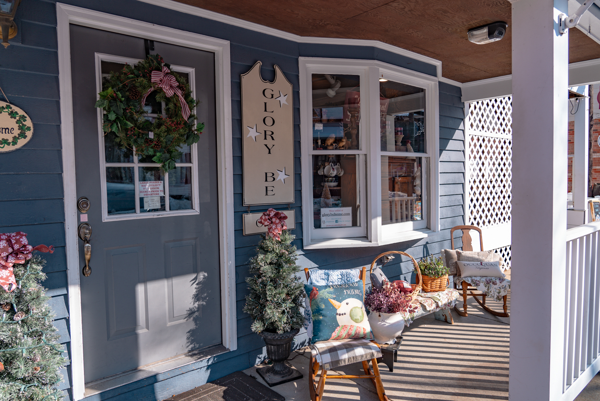 The exterior of a vintage shop with chairs and Christmas trees and ornaments.
