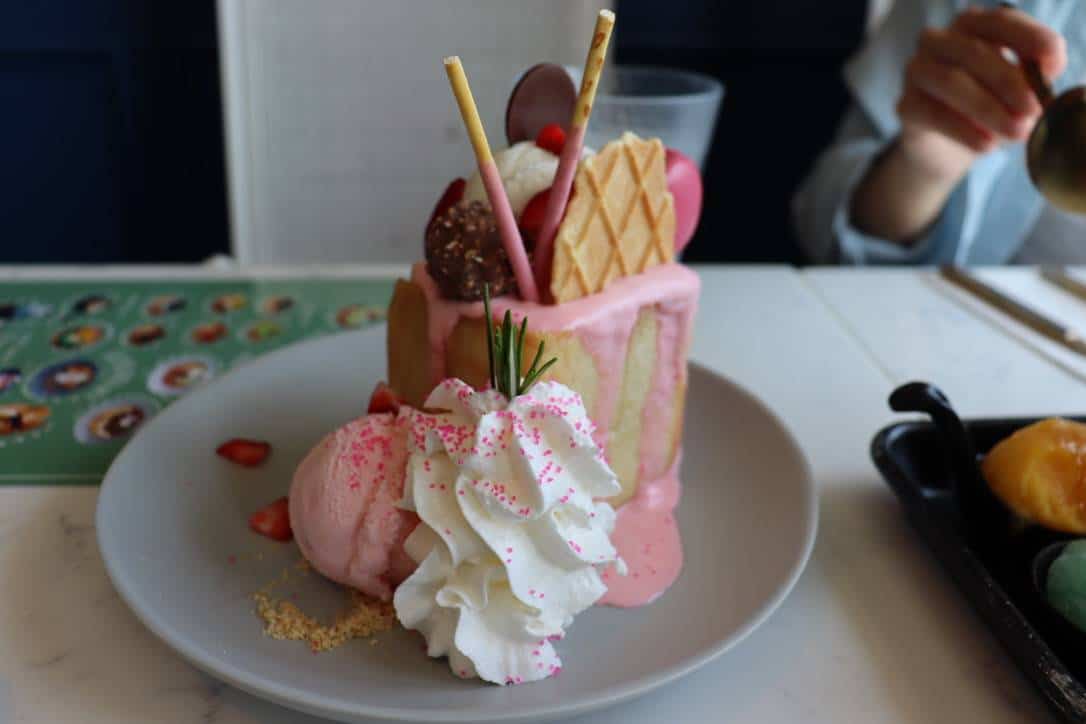 A slice of cake with whipped cream, waffle, ice cream, and other desserts.