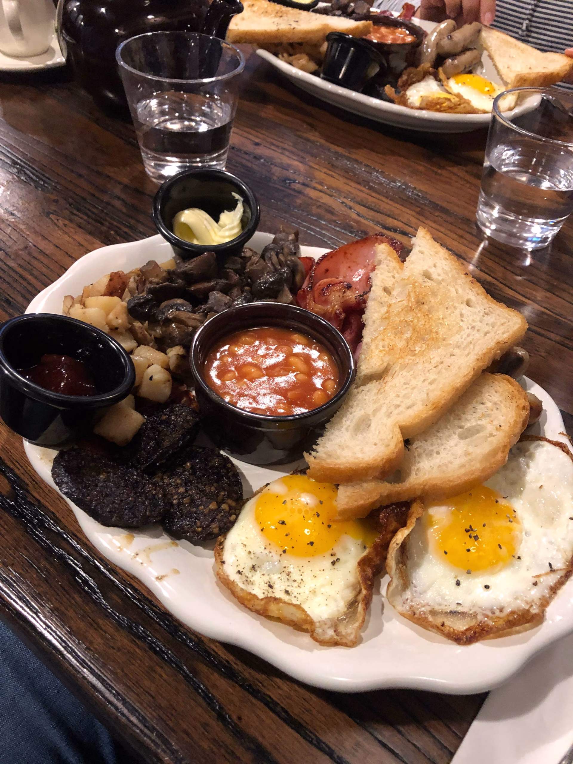 A breakfast plate with eggs, toast, beans, and other meat.