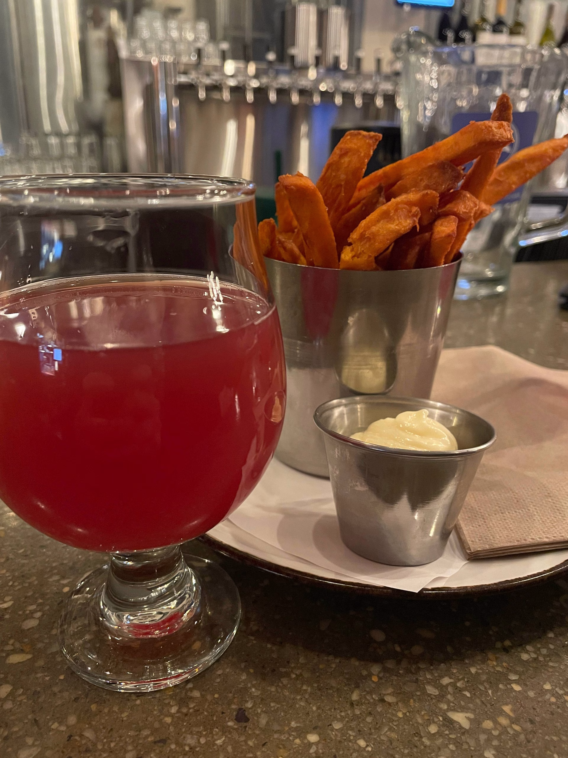 Red juice on a glass and a plate with fries and dip in separate stainless containers.