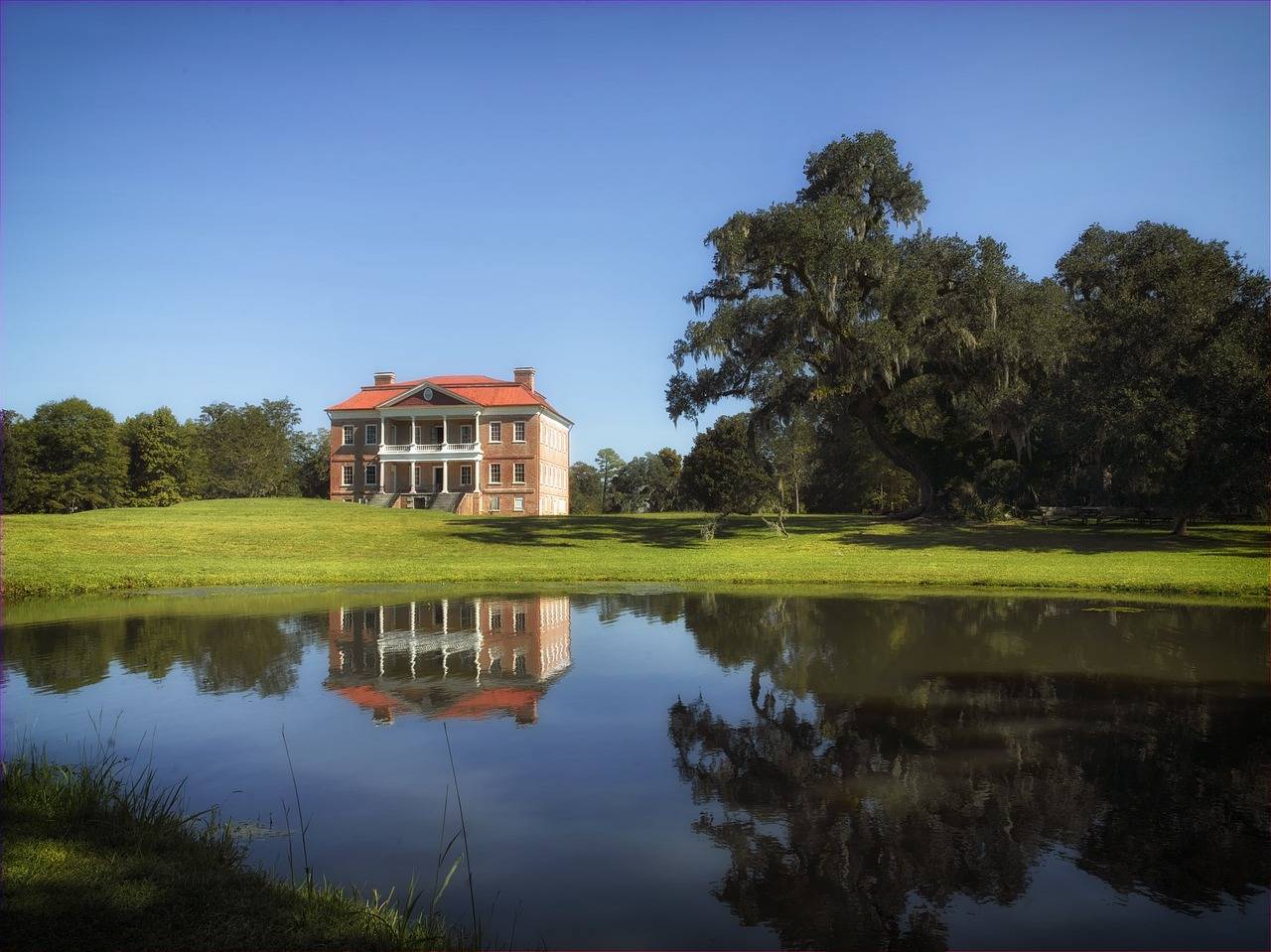 Drayton Hall building surrounded by a lake and some trees.