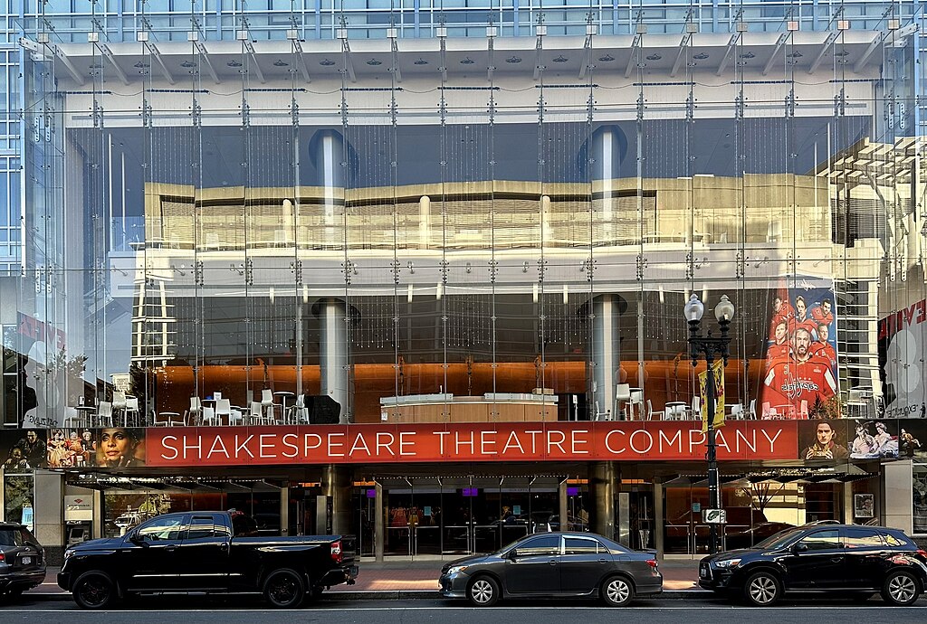The outside of a building with glass walls and with cars parked on the road side in Washington DC.
