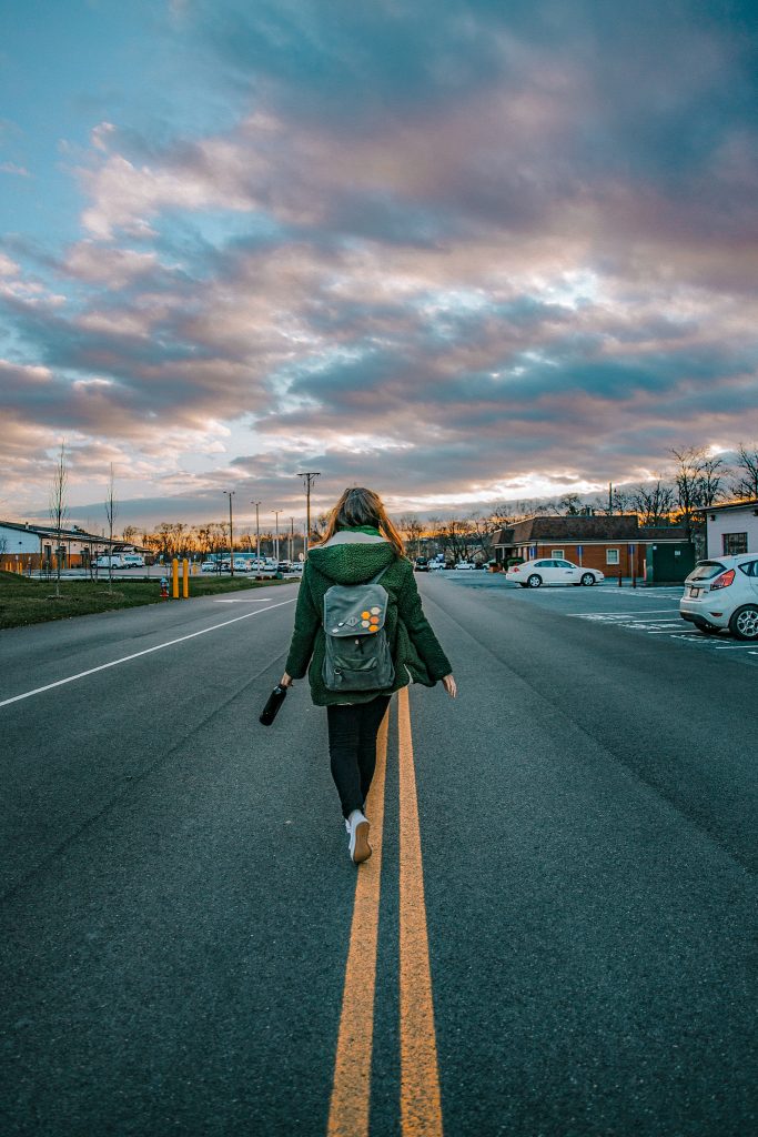 girl with a backpack walking on a road