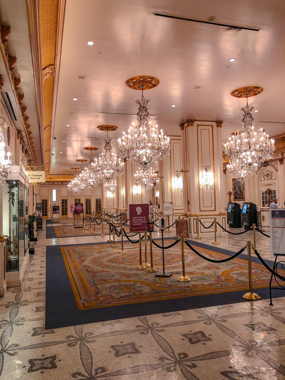 An empty hotel lobby with carpets and chandeliers.