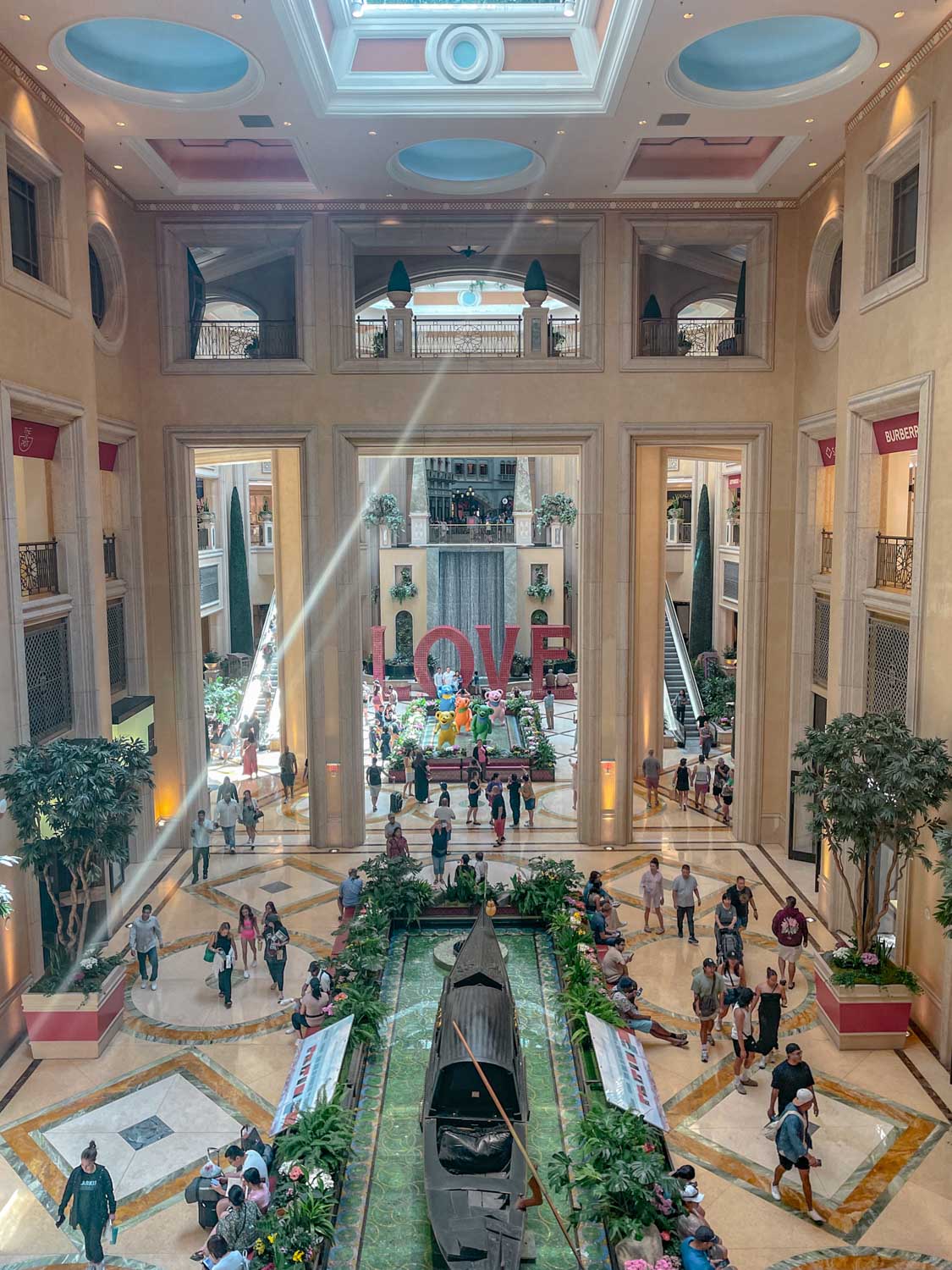 People walking inside a part of a hotel with high ceiling.