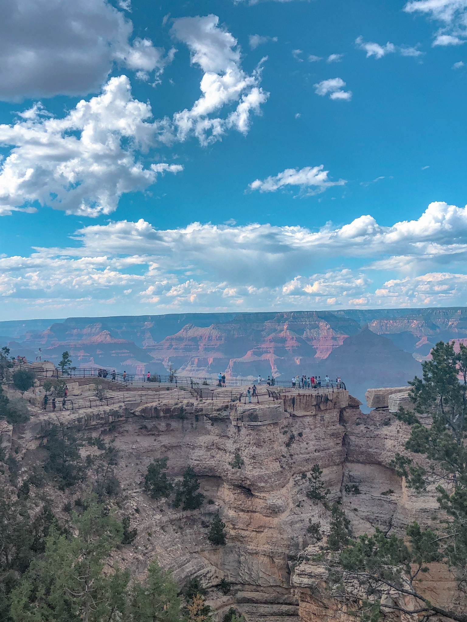 A viewpoint on the Grand Canyon South Rim with people.