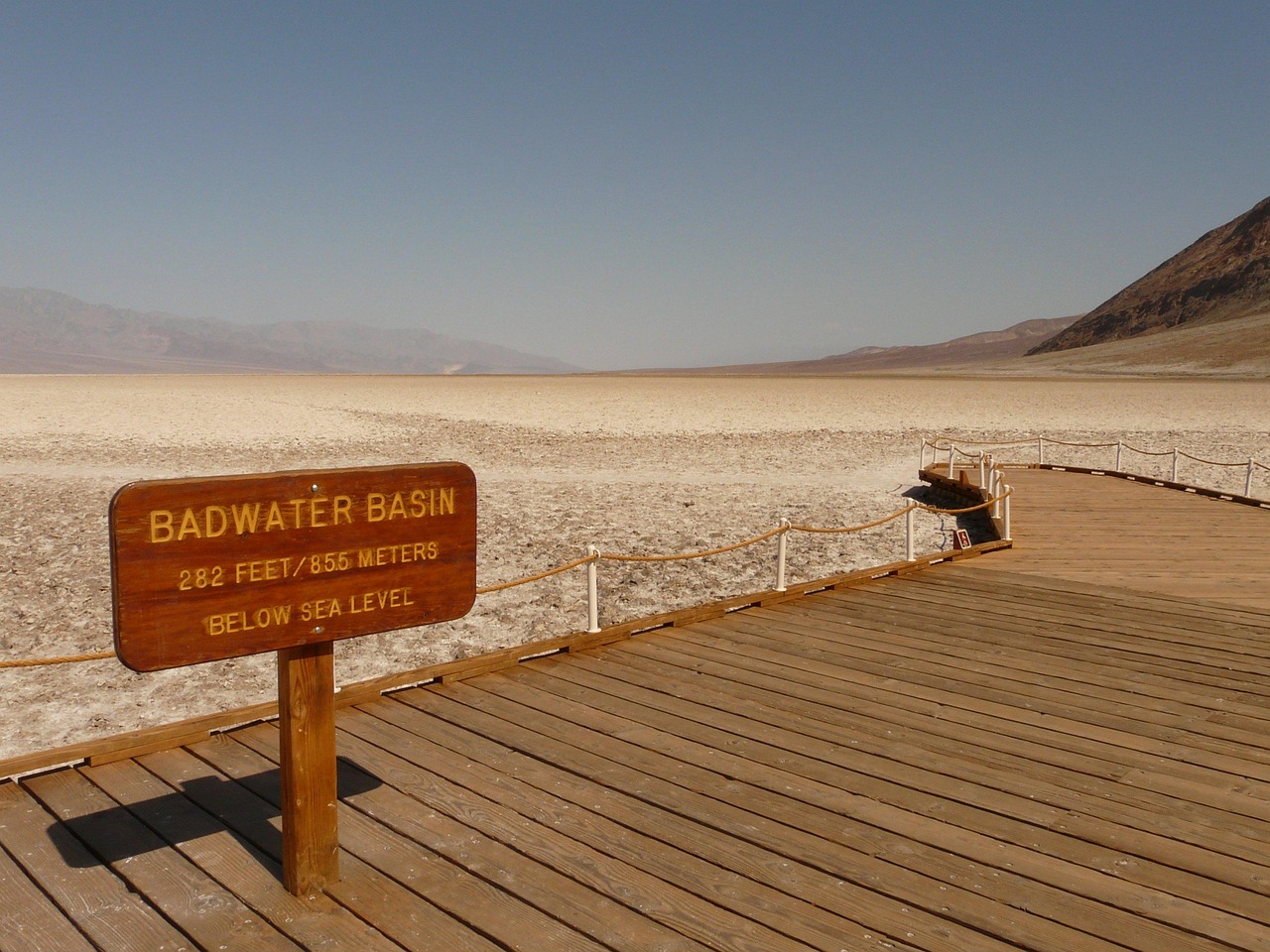 A wooden sign that says "Badwater Basin" on a wooden floor pathway.