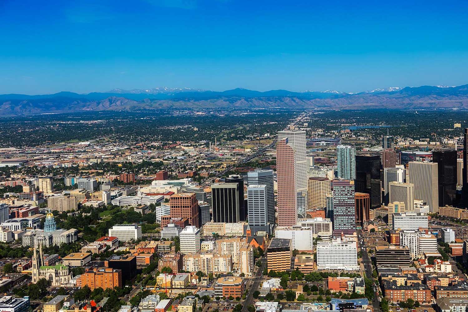 A city with many buildings and trees and with views of mountains in the background.