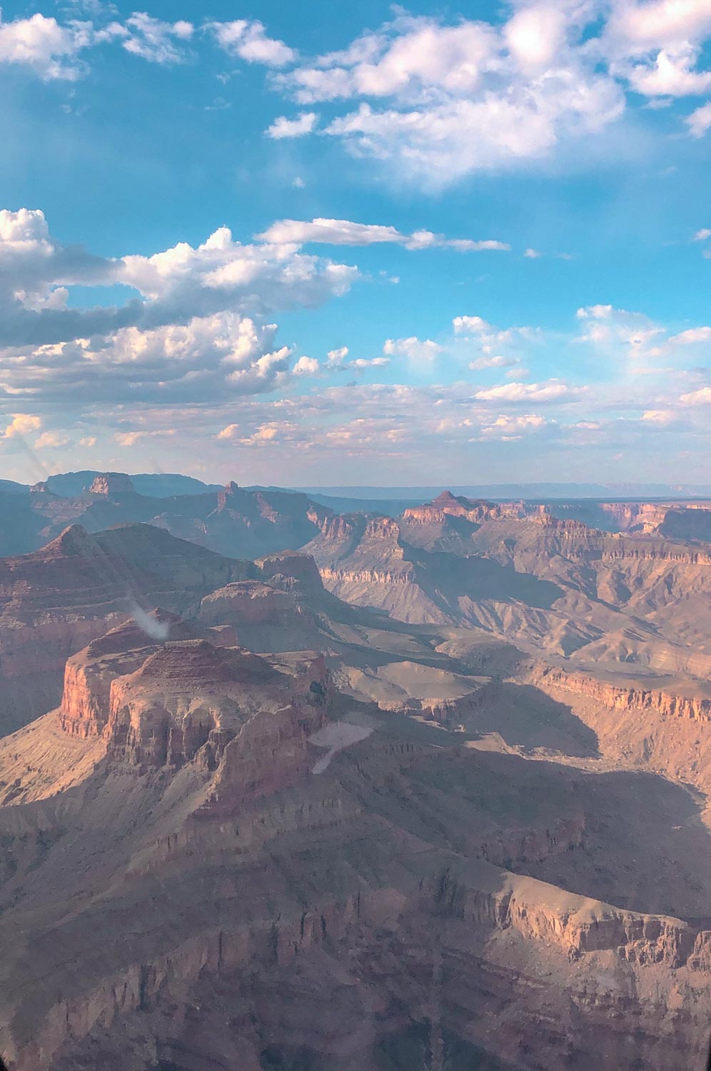 Canyons of the Grand Canyon South Rim under blue cloudy skies.