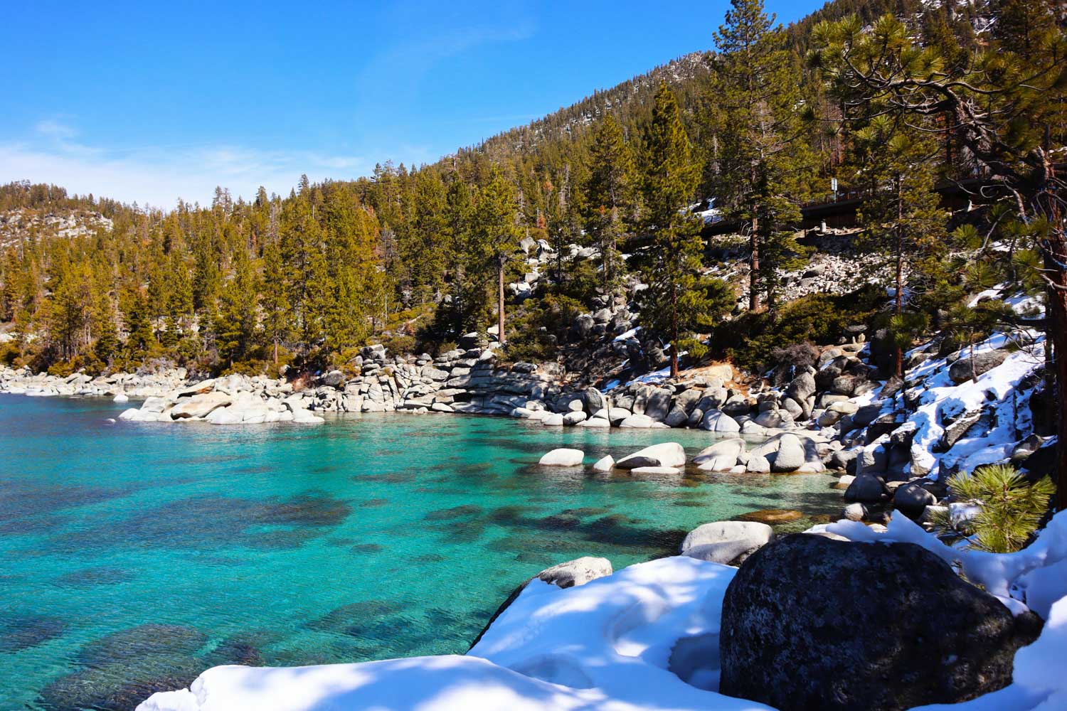 Blue lake surrounded by big stones and pine trees.