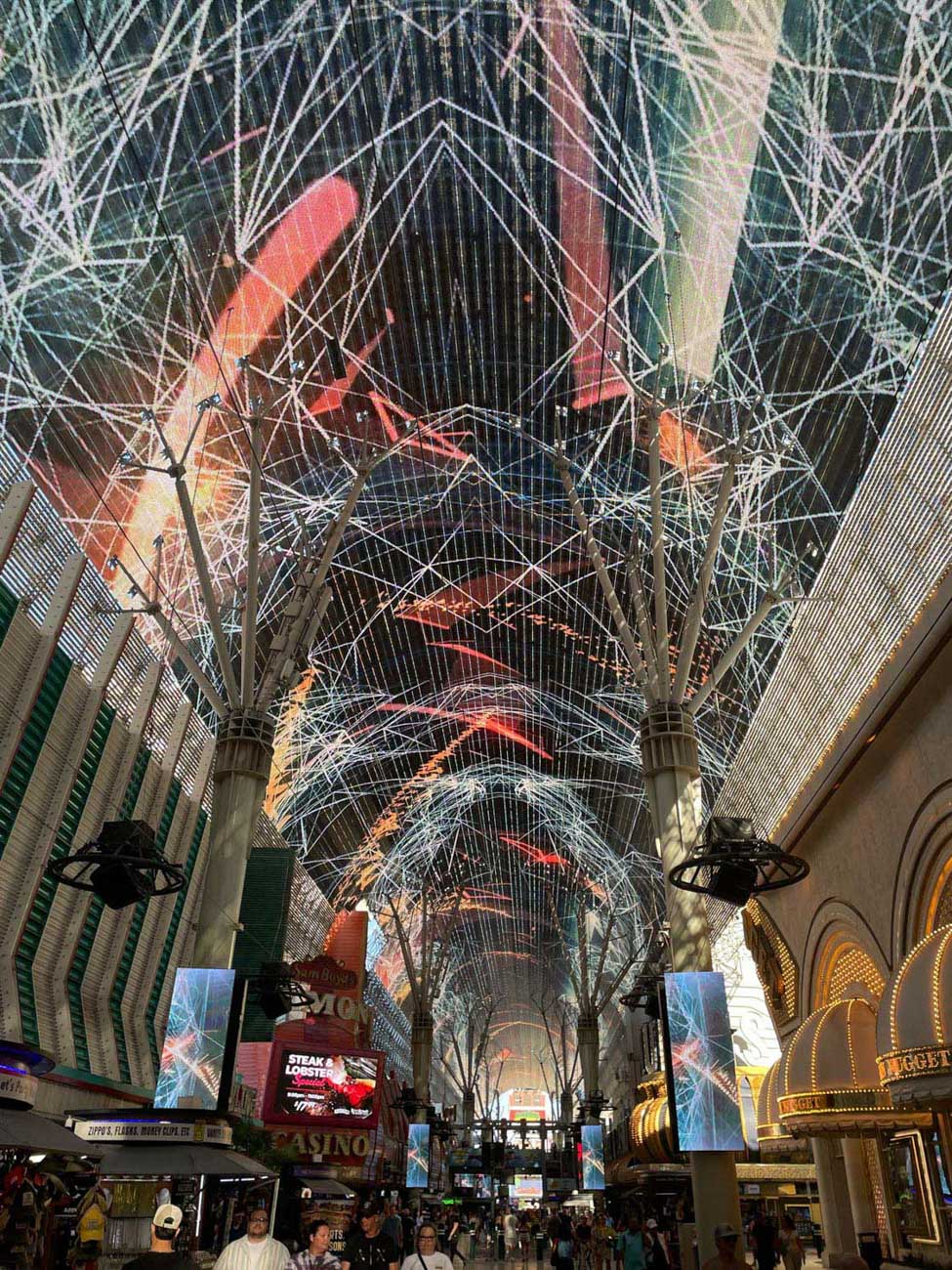 People walking on Fremont Street in Las Vegas with shade with ceilings that have a light show.