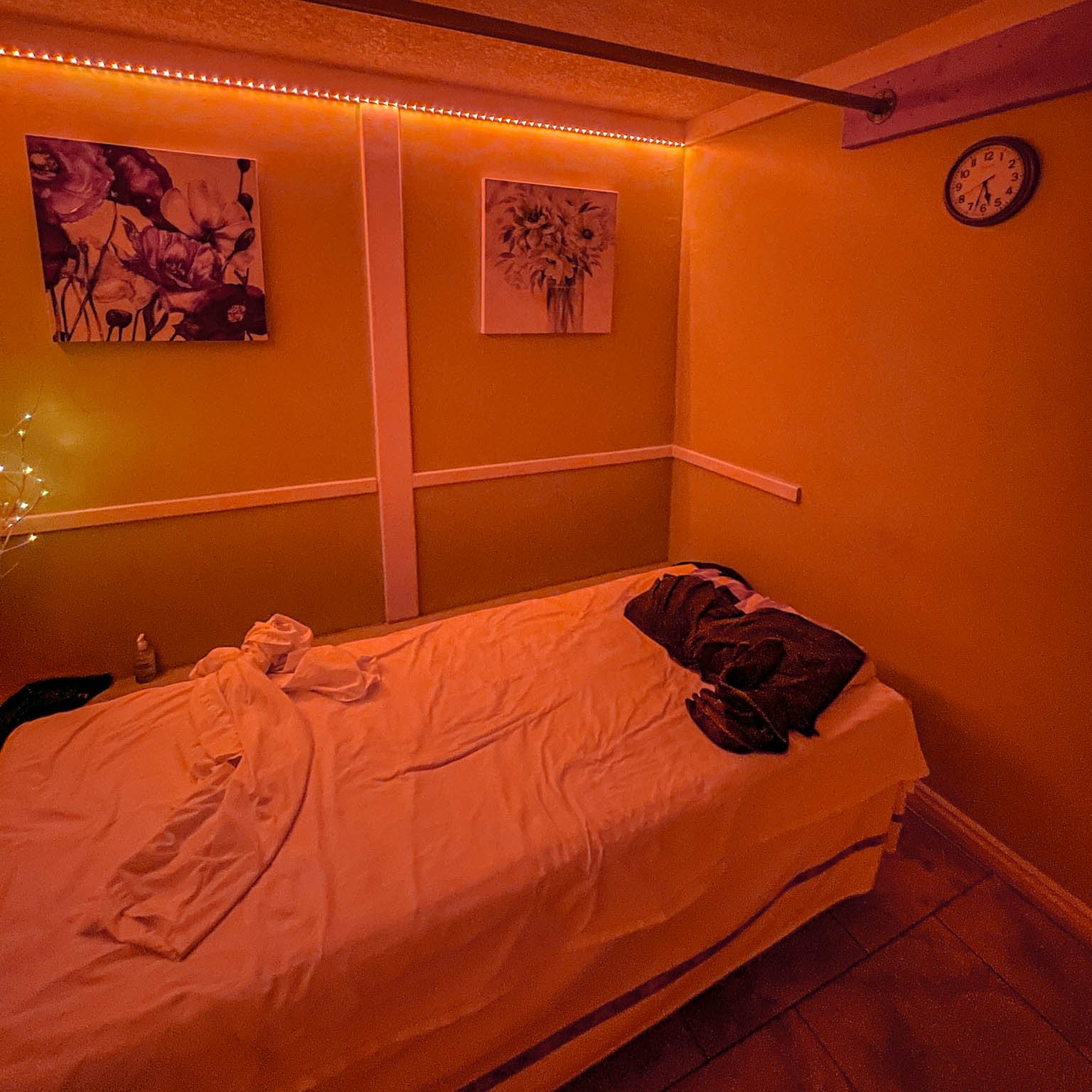 Inside a spa room with bed and red-orange lighting.