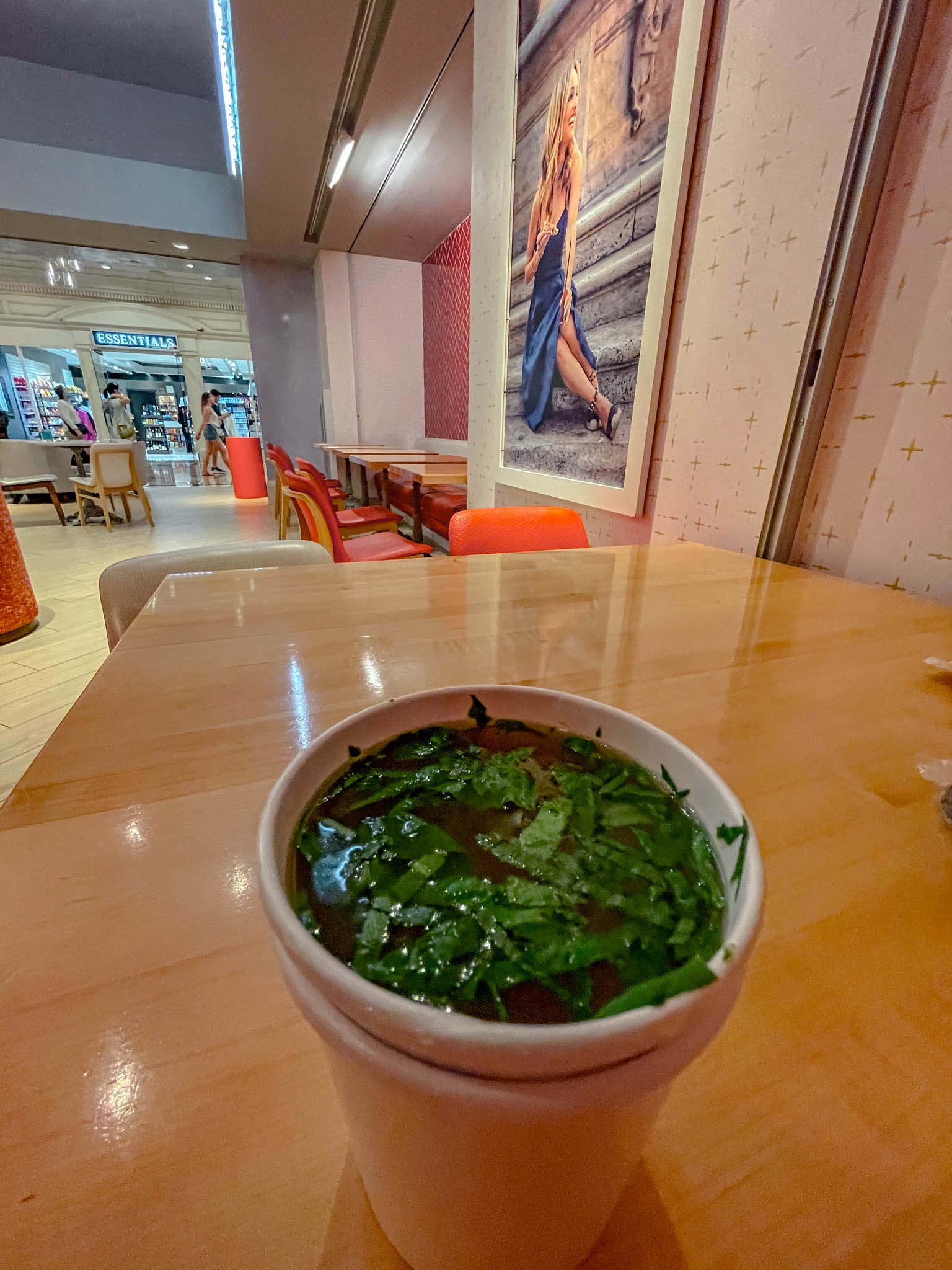 A cup of drink with herbs on a table.