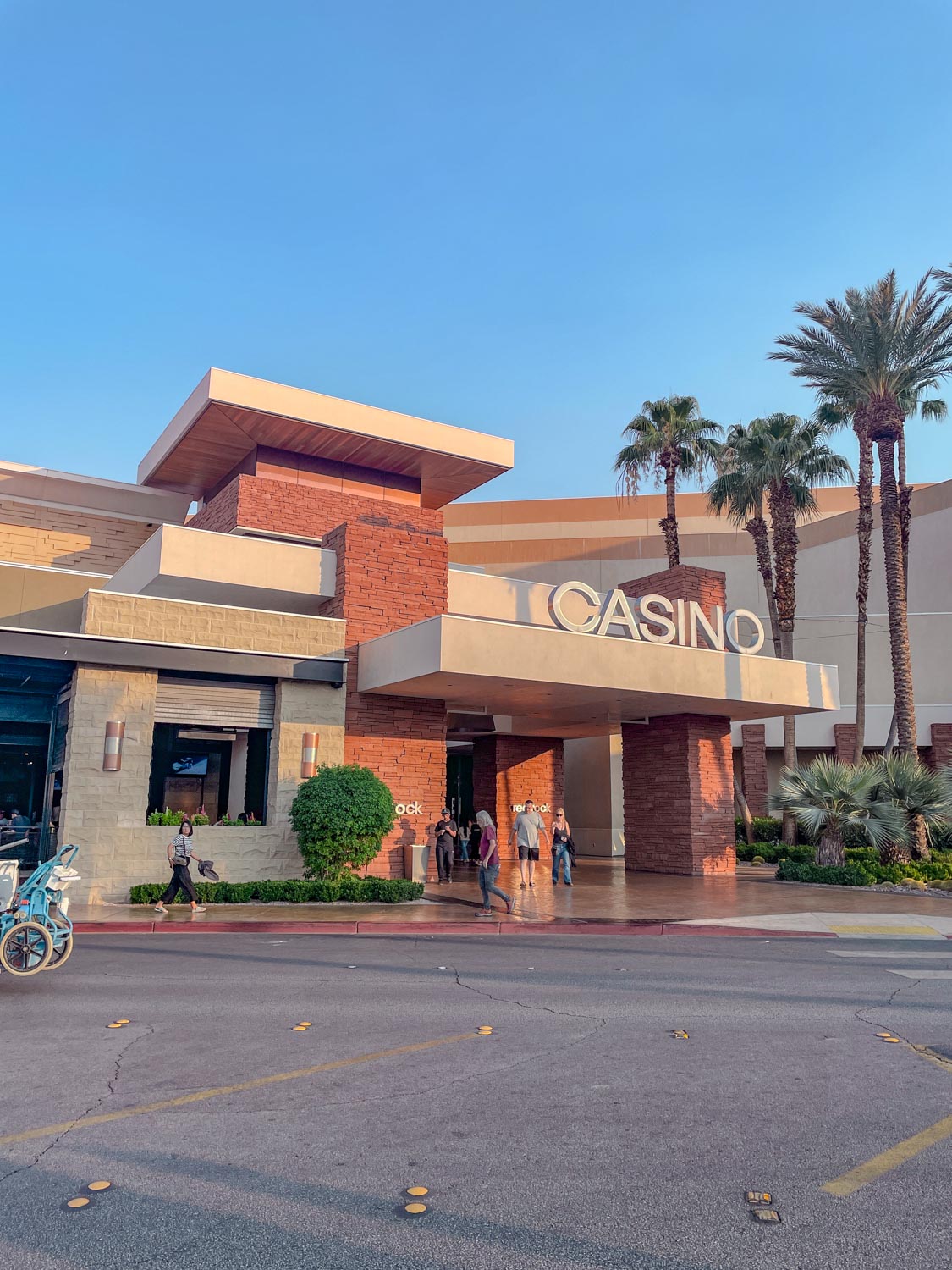 The entrance of Red Rock Casino Resort & Spa in Las Vegas surrounded by palm trees.