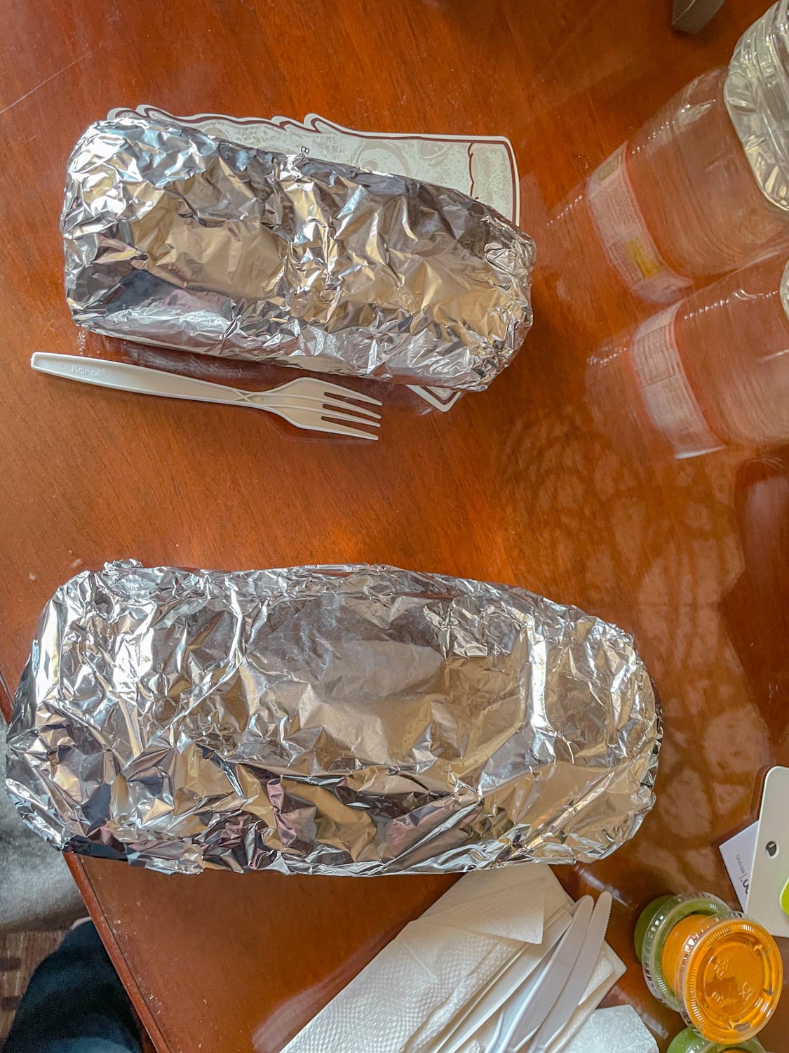 Burritos in foil resting on a table.