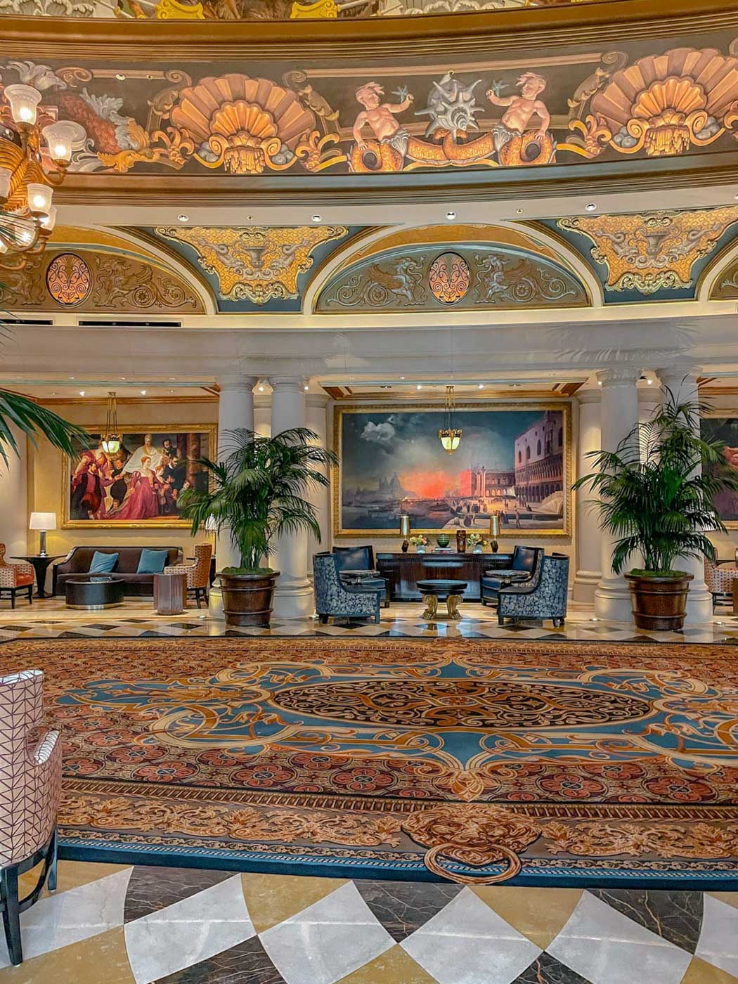 A carpeted lobby of a hotel with colorful flooring and painted ceilings.