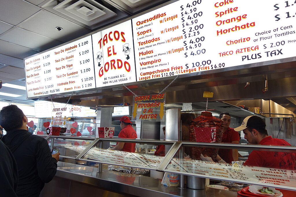 People working and people choosing from the menu counter at Tacos El Gordo in Las Vegas.