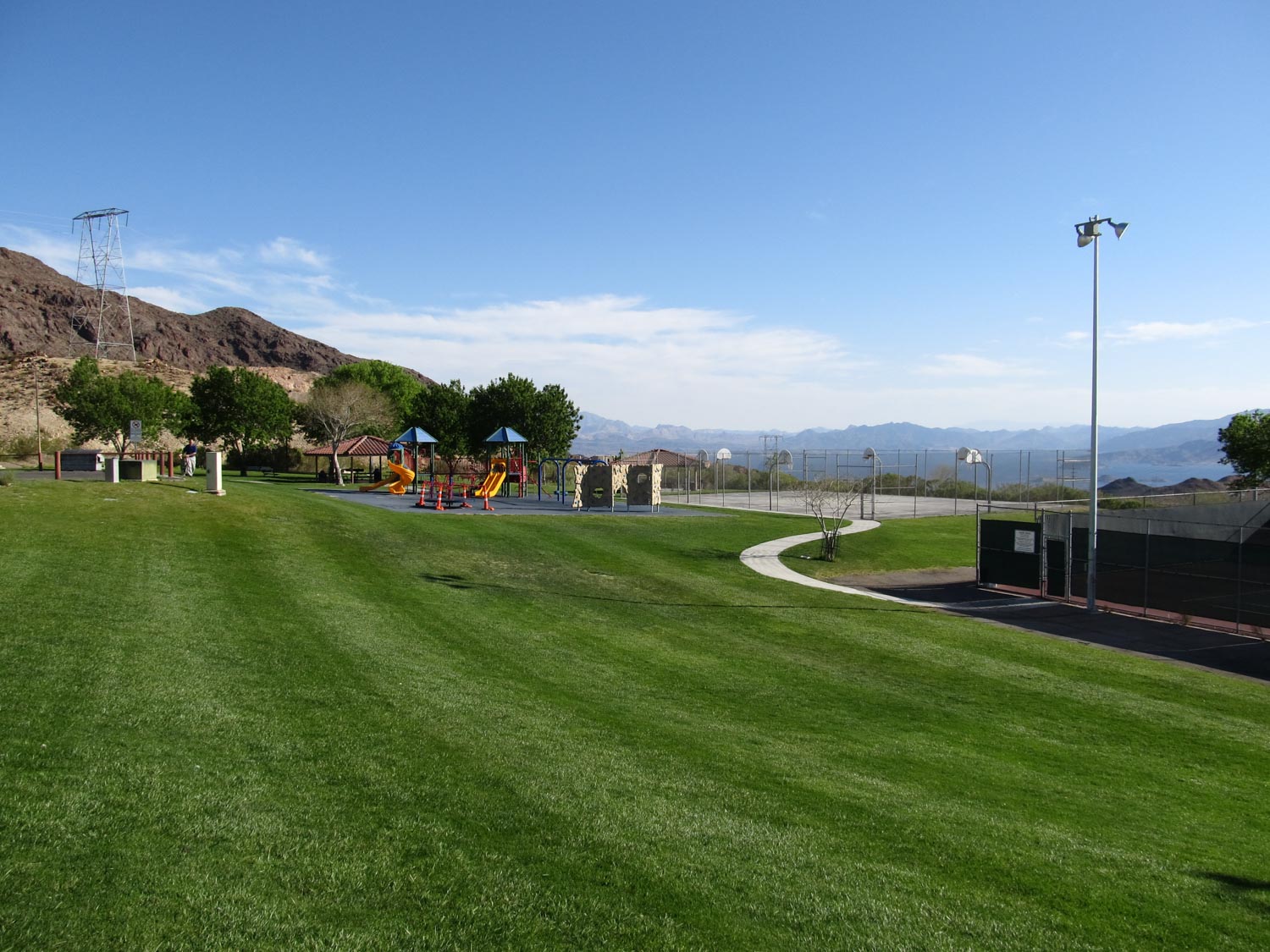 Hemenway park with playground and trees in Boulder City with rocky mountains in the background.