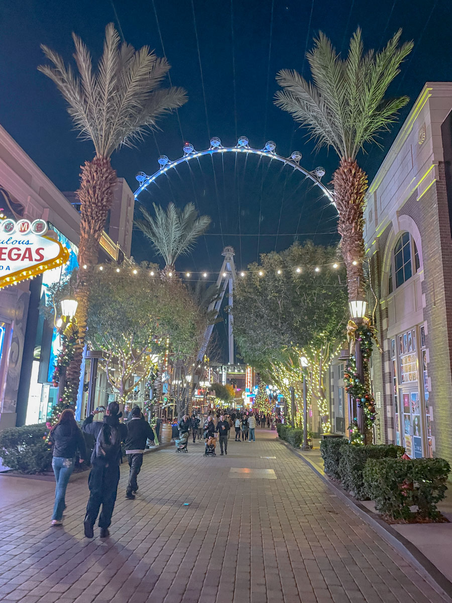 LINQ Promenade with holiday decor, few people, and ferris wheel.