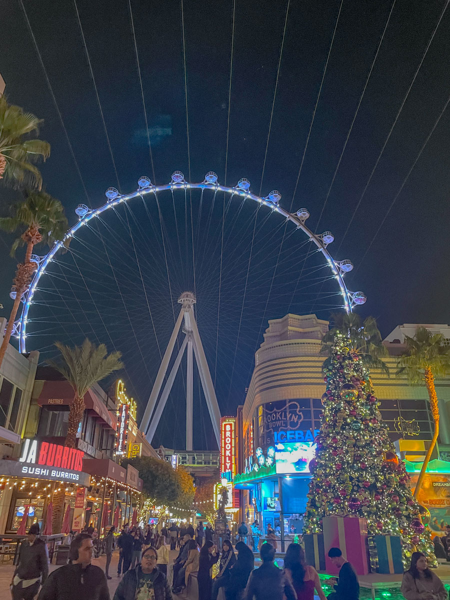 LINQ Promenade with holiday decor, many people, and ferris wheel.