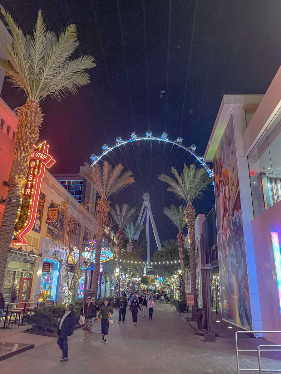 Ferris wheel and palm trees at the LINQ Promenade in Las Vegas at night.