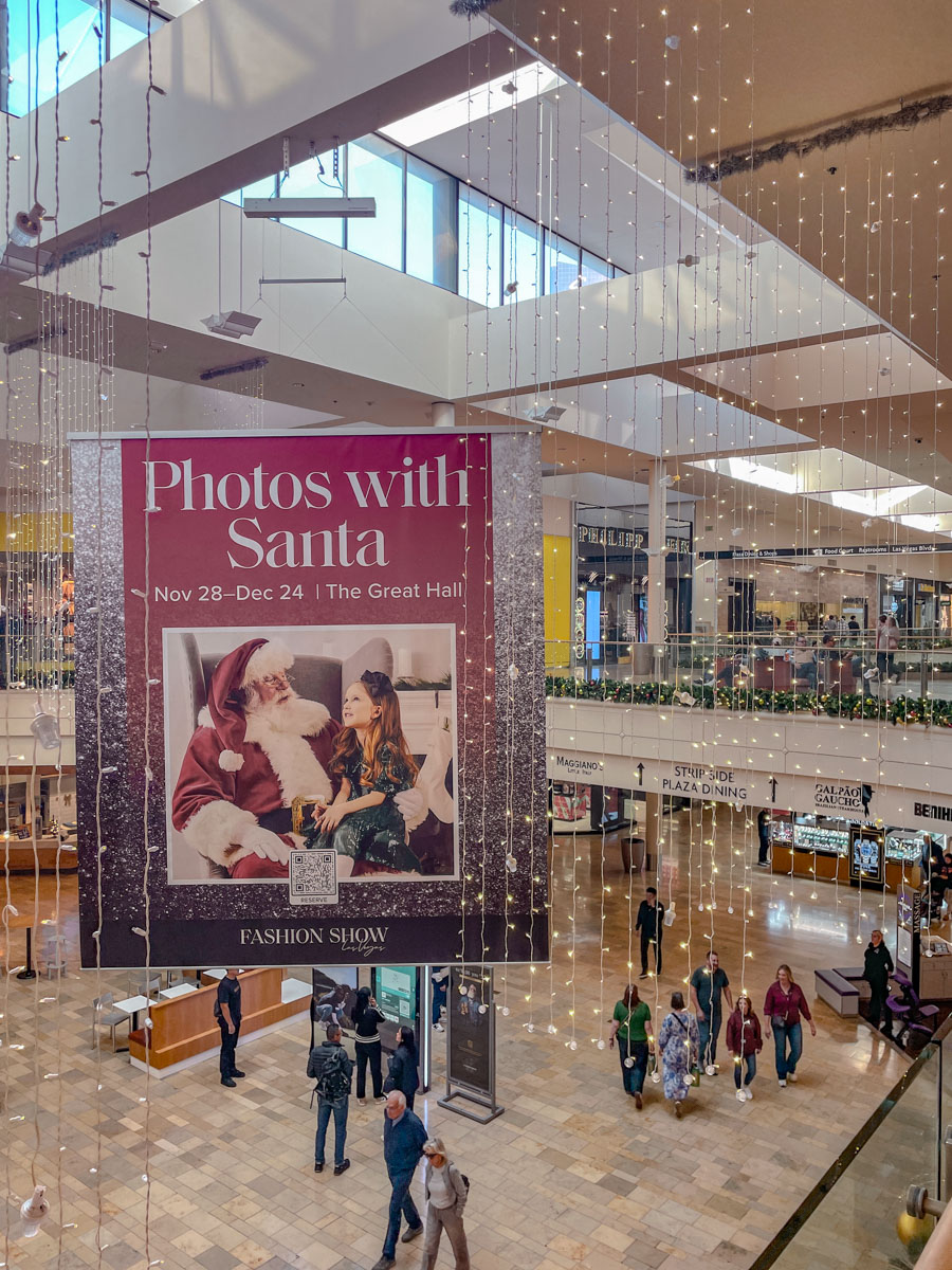 Fashion Show Mall with holiday lights and poster "Photos with Santa".