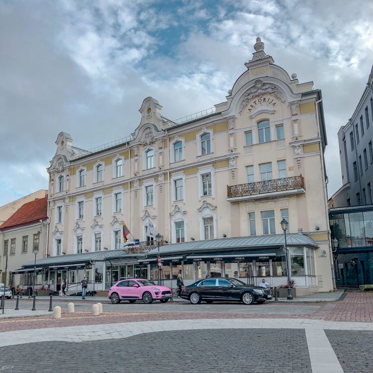 The facade of Astorija Hotel in Vilnius with cars parked outside.