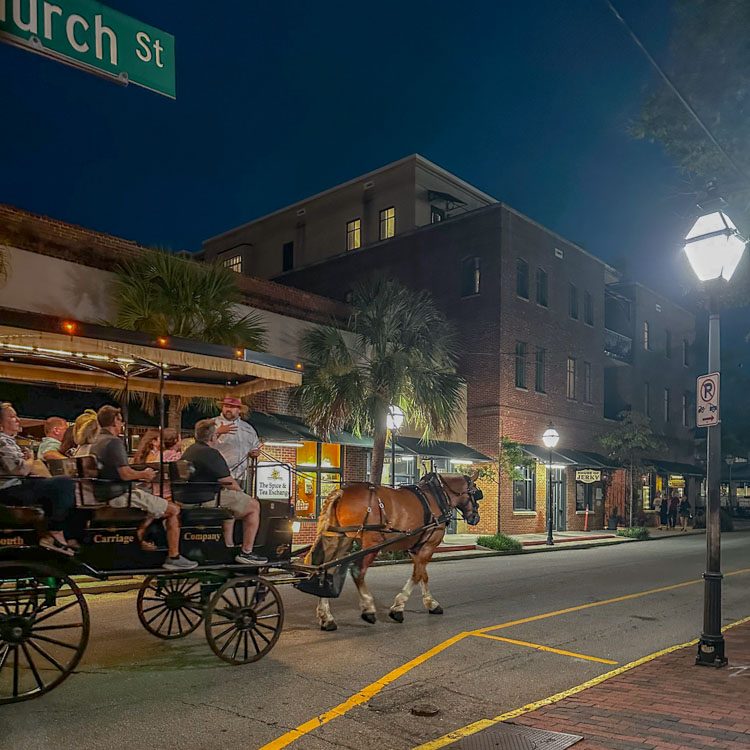 People riding a horse carriage at night in Charleston, South Carolina.