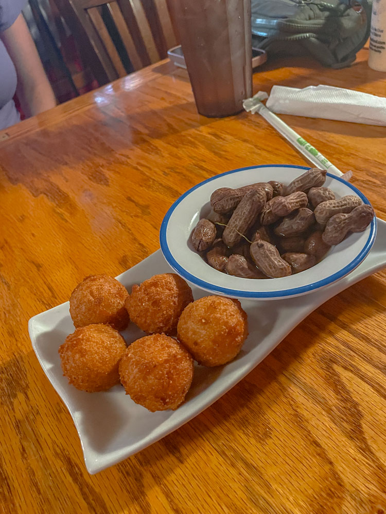 Fried food and boiled peanuts on plates and dish on a table.