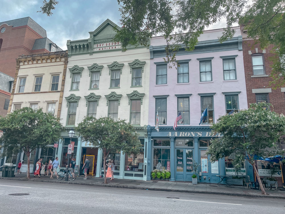 People walking on the sidewalk in front of colorful buildings in Charleston, South Carolina.