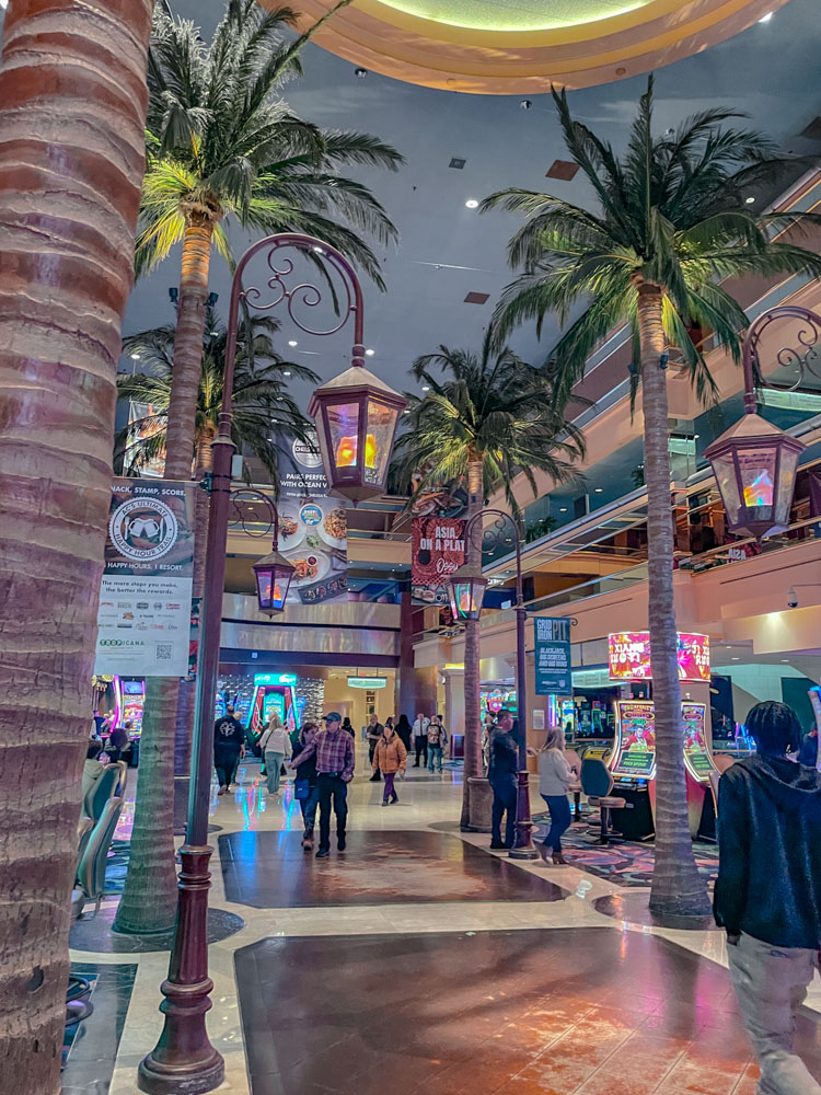 People walking inside Tropicana hotel with palm trees.