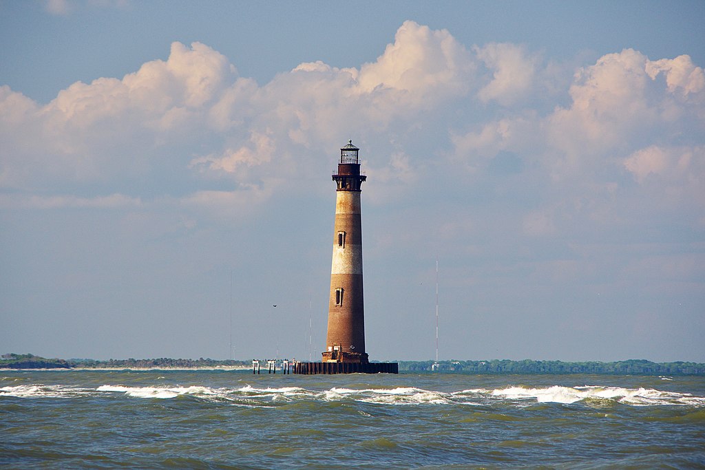 Lighthouse with striped paint in the middle of the sea.