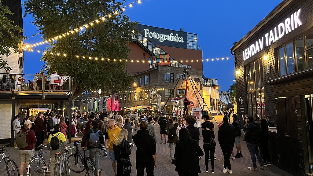 People in the middle of Telliskivi Creative City in Tallinn, Estonia with the Fotografiska and Lendav Taldrik buildings in the background.