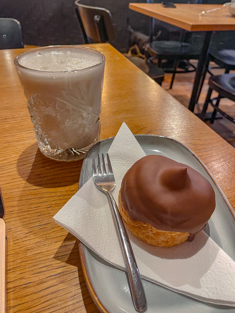 Pastry on a plate and a drink on a glass cup.