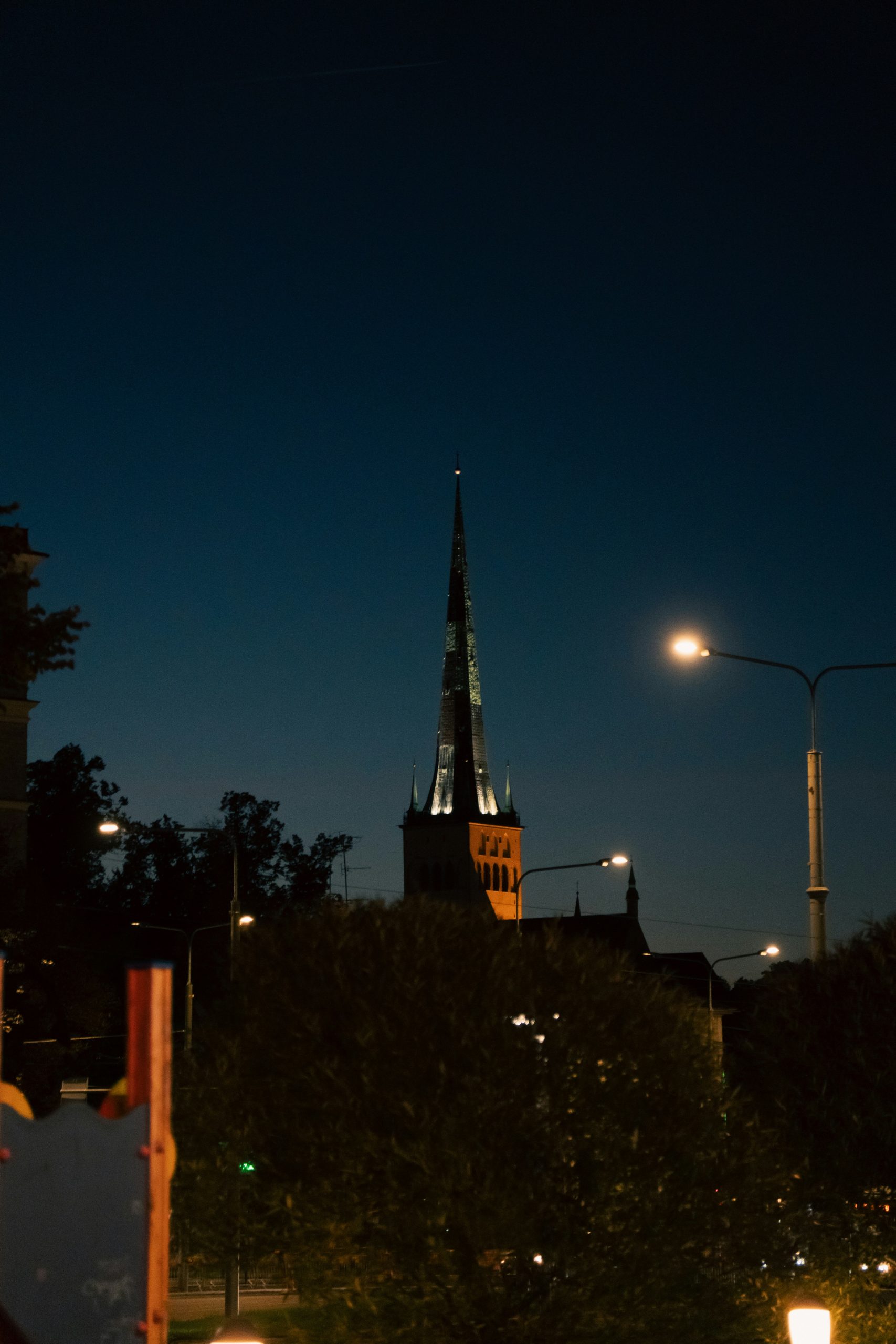 A city street at night with a clock tower in the background in Tallinn, Estonia.