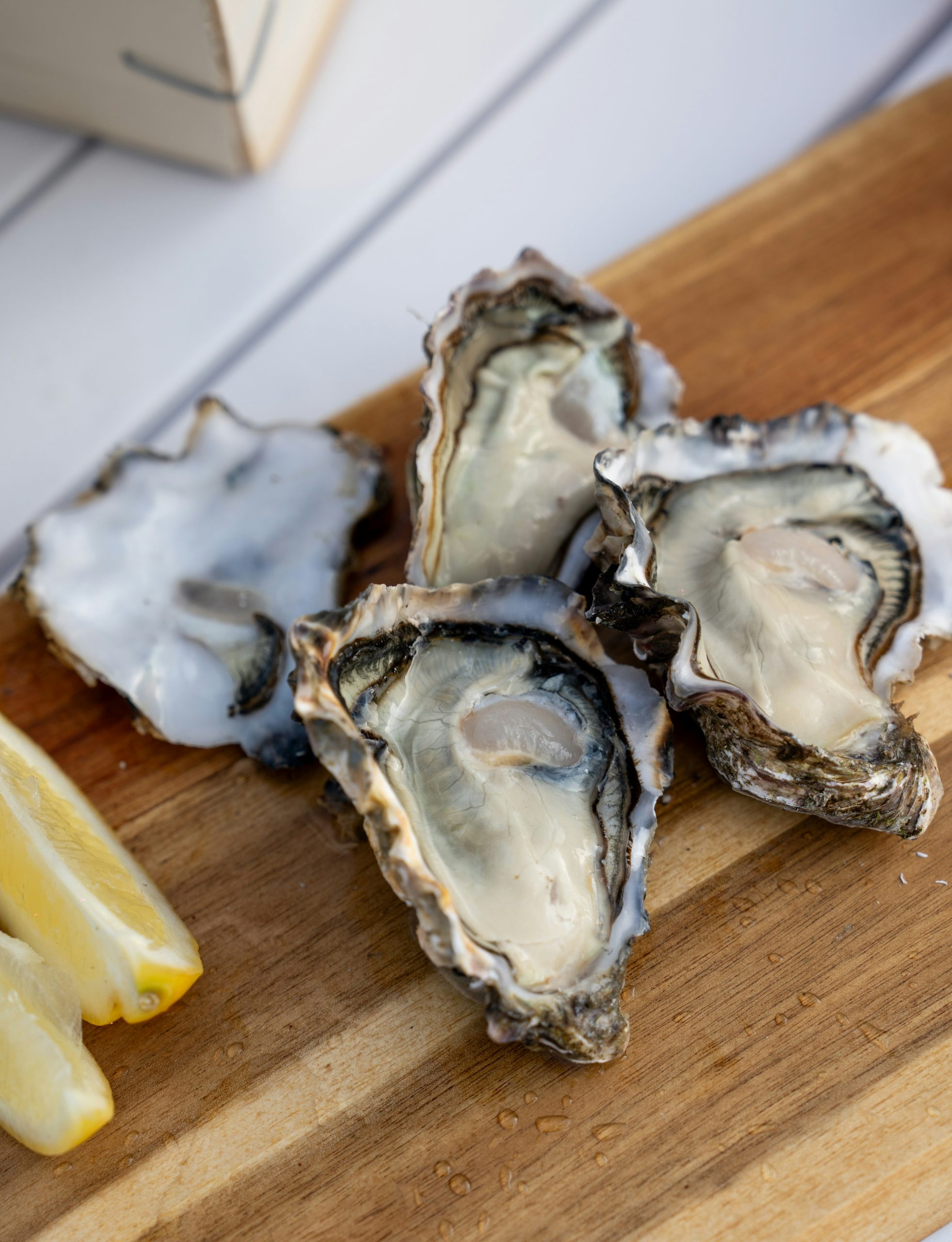 Oysters and slices of lemons on a wooden cutting board.