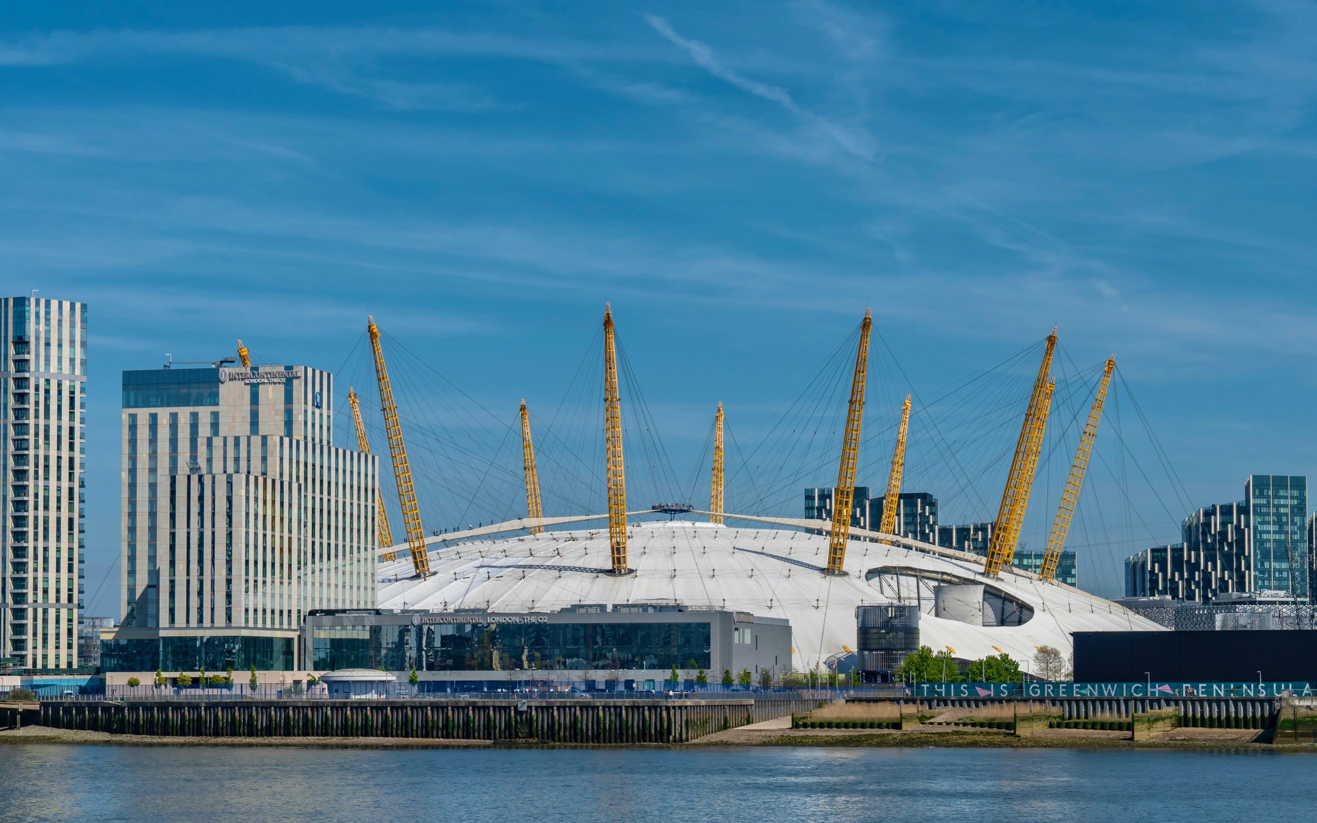 A view of an arena with a dome-like roof near a body of water in London, England.