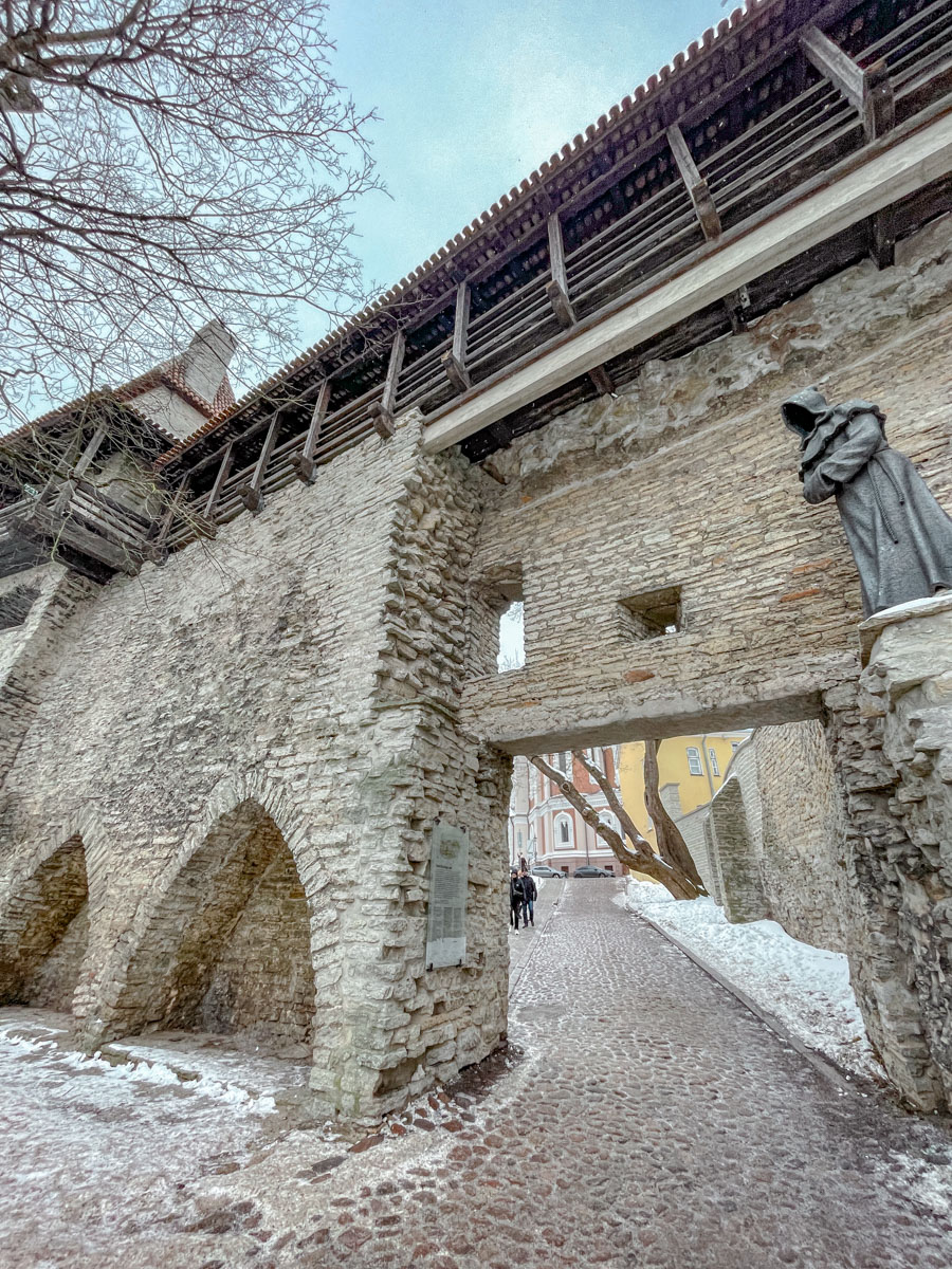 Stone walls of Tallinn, Estonia with sculpture and entrance to another side of the wall.