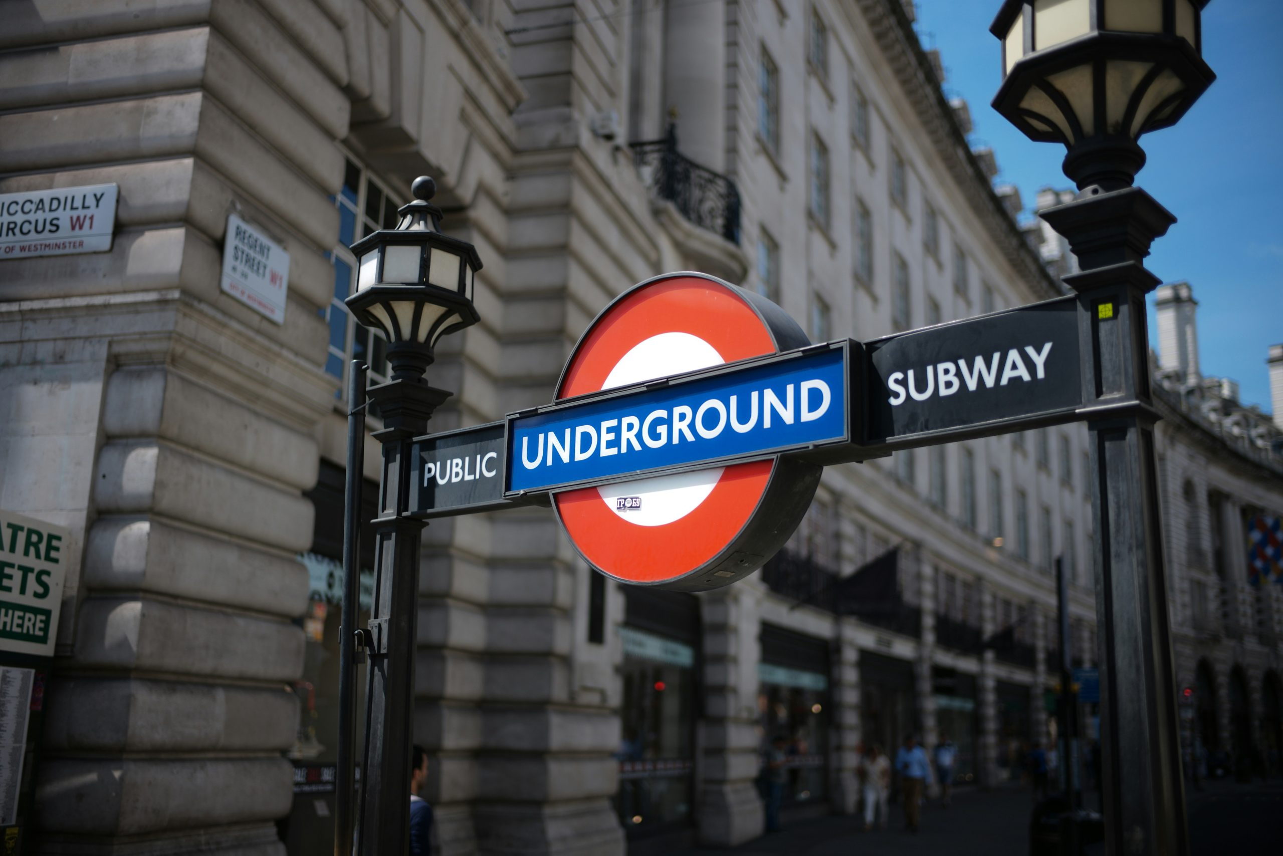 Street sign that says "Public Underground Subway" between lampposts in front of a building in London.