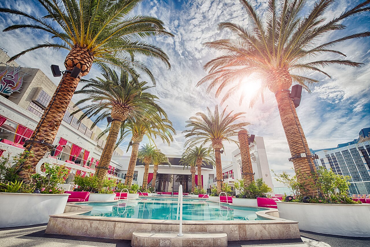A swimming pool area of a hotel with palm trees.