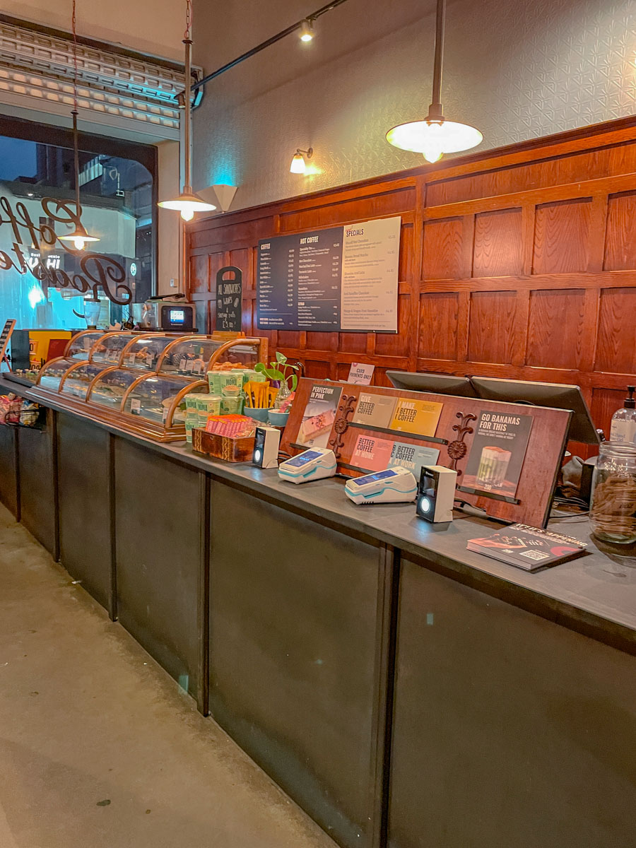 The counter of a coffee shop decorated with overhead lamps.