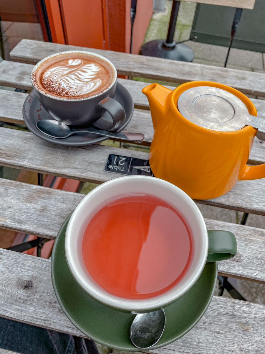 Cups of coffee and tea on ceramic coasters on a wooden table.
