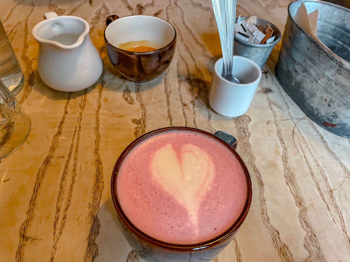 A cup of beetroot ginger latte with latte art on a table.