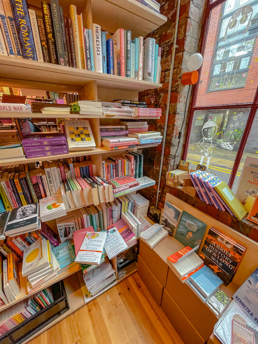 Shelves of colorful books at a corner of a bookstore with window in Sheffield, UK.