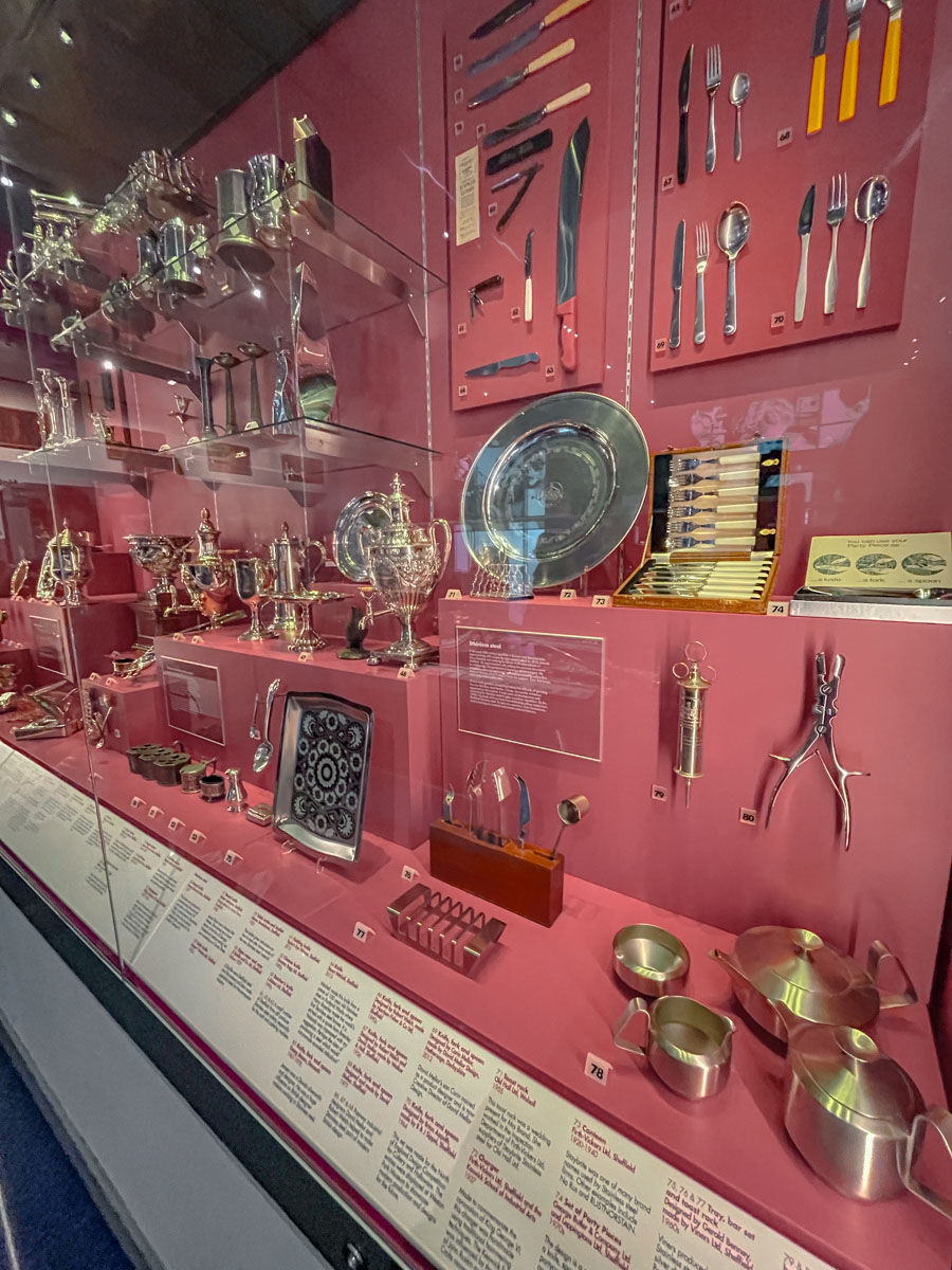 Various metal products on a wall with red backdrop and inside a glass wall.