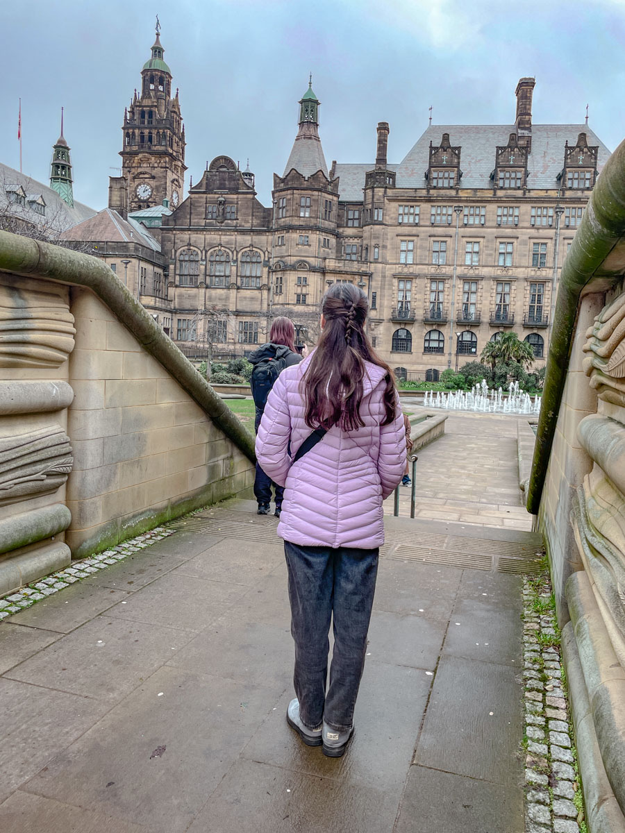 A woman in purple jacket and dark pants looking at the Peace Gardens in Sheffield.