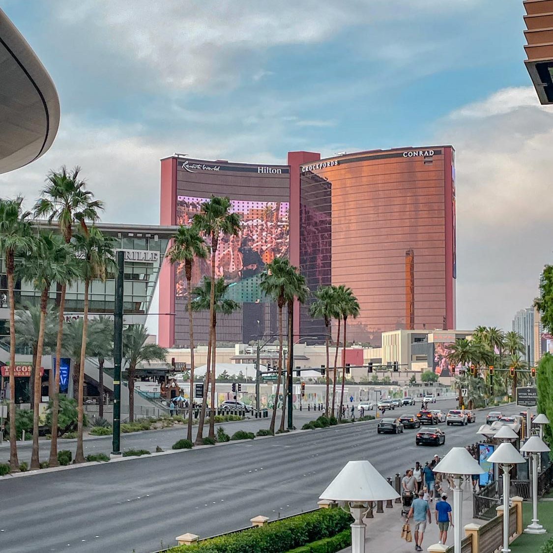 People, cars, and trees outside the Resorts World Las Vegas buildings.