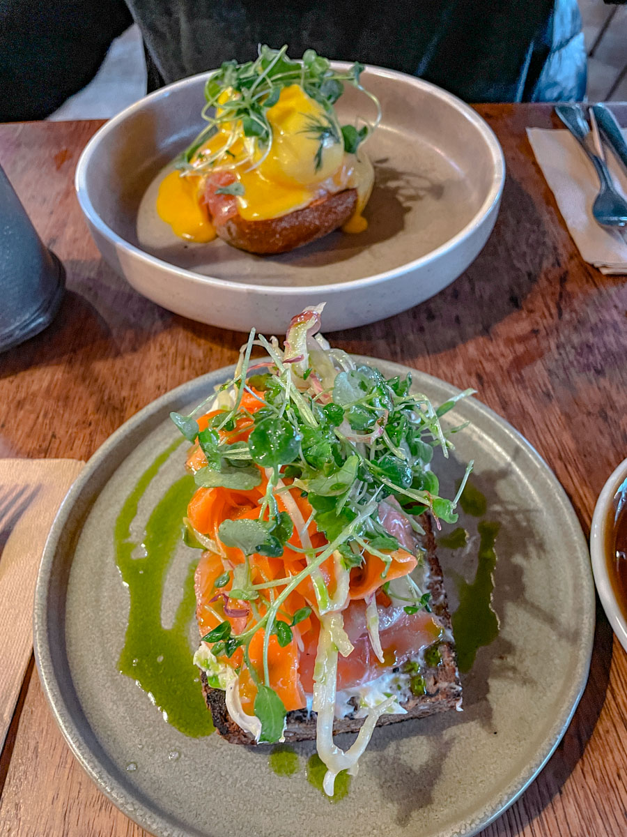 Two plates of food garnished with greens on a table.