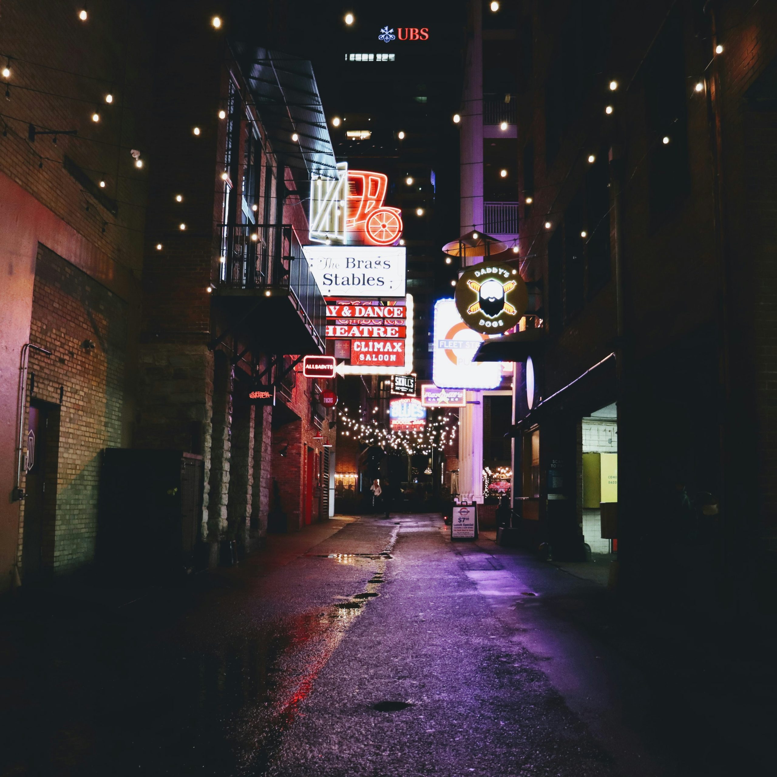 A dark alley in Nashville with some bar signs.