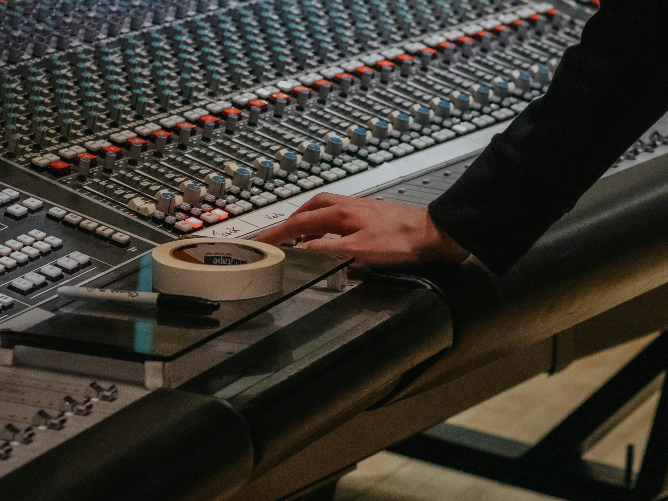 A hand operating a professional audio mixing console in a studio in Nashville.